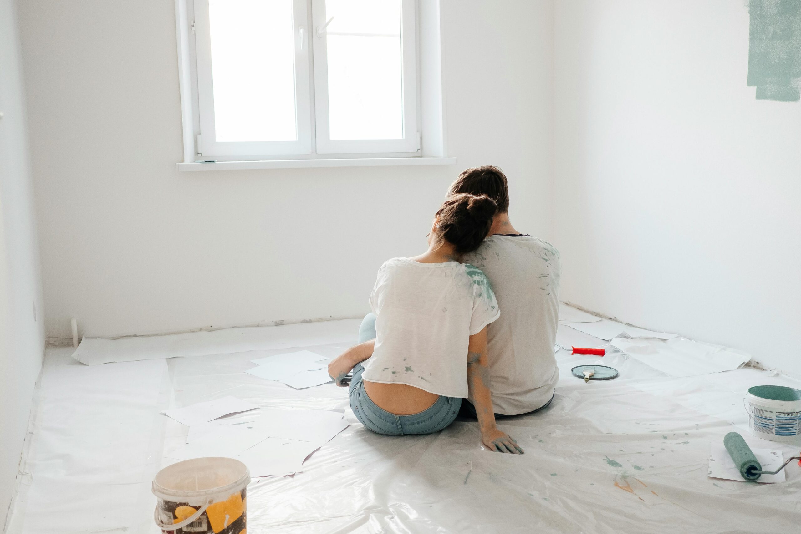 A couple sitting on the floor, taking a break from painting their home.